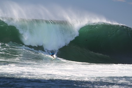 Surfer with big wave following them