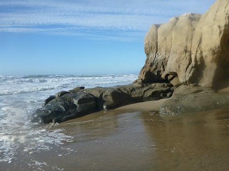 waves hitting the beach along a rocky shoreline