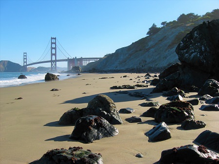 A rocky beach shore with the Golden Gate Bridge in the background.