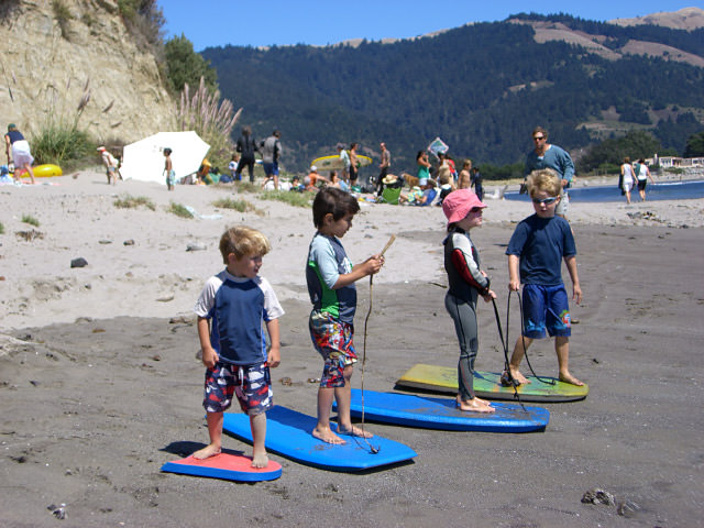 kids standing on boogie boards on the beach